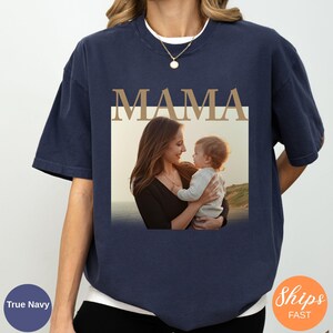May include: Navy blue t-shirt with the word "MAMA" in a gold font above a photo of a mother and child. The photo is in a white rectangle. The shirt is a relaxed fit.