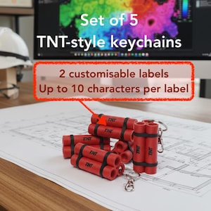 Könnte beinhalten: Ein Set aus 5 roten Schlüsselanhängern im TNT-Stil mit zylindrischen Formen, die durch schwarze Bänder verbunden sind. Der Text "Set of 5 TNT-style keychains" und "2 customisable labels Up to 10 characters per label" ist sichtbar.