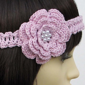 May include: A pink crocheted headband with a large flower and pearl embellishments.