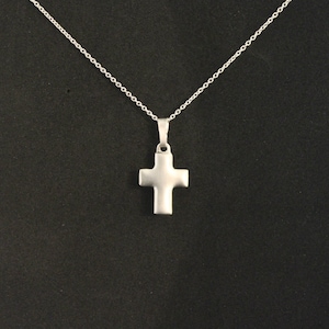 May include: A silver chain necklace with a simple silver cross pendant.