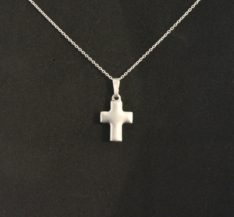 May include: A silver chain necklace with a simple silver cross pendant.