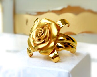 Può includere: Un anello color oro con un designo di rosa dettagliato. La rosa è tridimensionale e ha un aspetto realistico.