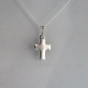 May include: A silver cross pendant on a silver chain necklace.