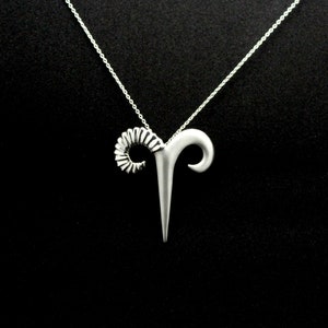 May include: Silver necklace with a ram's head pendant. The pendant is detailed with a curled horn and a pointed head.