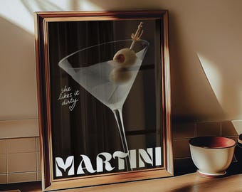 May include: A framed print featuring a martini cocktail with olives. The artwork has the word "MARTINI" in bold white letters at the bottom and the phrase "she likes it dirty" in cursive. The frame is a warm brown color.