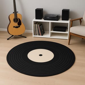 May include: A round black rug designed to resemble a vinyl record. The rug features concentric grooves and a beige center. A guitar, stereo equipment, and a chair are in the background.