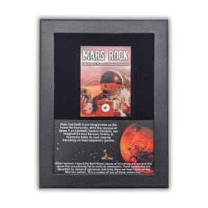 Può includere: Esposizione incorniciata con un'etichetta "MARS ROCK" e un'immagine di un astronauta su Marte. L'esposizione include testo sui meteoriti marziani e l'esplorazione spaziale. La cornice è nera.