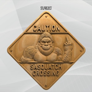 May include: Wooden sign with the text "CAUTION SASQUATCH CROSSING" and a carved image of a smiling Sasquatch giving the middle finger. The sign is diamond-shaped with a light brown color.