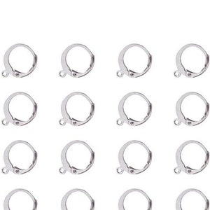 May include: A collection of sixteen silver-colored leverback earring findings. Each finding has a circular design with a hinged lever and a small loop for attaching a charm or bead. The findings are arranged in a grid pattern.