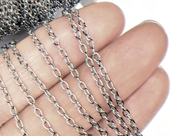 May include: A close-up of a silver chain, with multiple strands of the chain laid out on a hand. The chain is made of small, oval-shaped links.