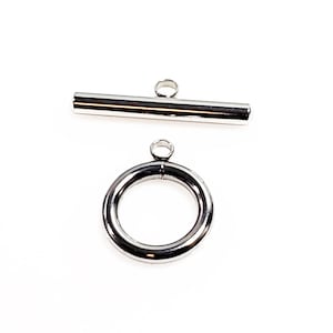 May include: Silver-toned metal toggle clasp with a round ring and a straight bar. The clasp is used for necklaces, bracelets, or other jewelry.
