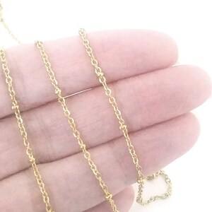 May include: A gold chain necklace with small beads. The chain is delicate and has a subtle shimmer.