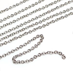 Puede incluir: Una cadena de plata con un delicado dise&ntilde;o de eslabones redondos. La cadena est&aacute; dispuesta en un patr&oacute;n suelto y fluido sobre un fondo blanco.