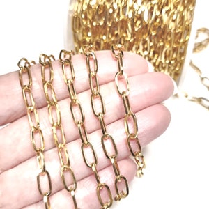 May include: Gold chain with oval links. The chain is shown in a hand, with multiple strands of the chain laid out side by side.