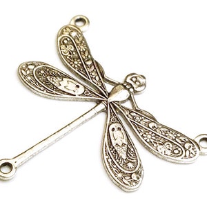 Puede incluir: Encanto de lib&eacute;lula de metal plateado con intrincados detalles florales. El encanto tiene dos bucles para sujetarlo a joyas u otras manualidades.
