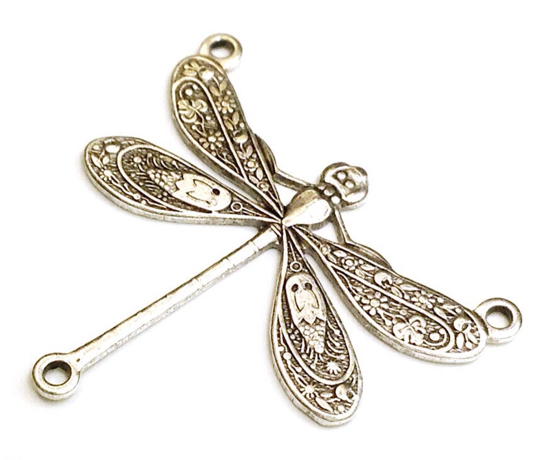 Puede incluir: Encanto de lib&eacute;lula de metal plateado con intrincados detalles florales. El encanto tiene dos bucles para sujetarlo a joyas u otras manualidades.