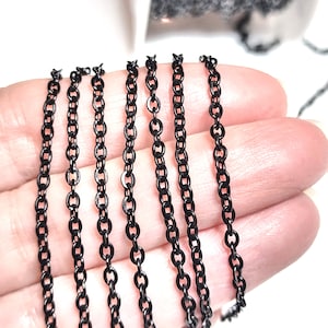 May include: Black chain in various sizes, shown on a hand. The chain is made of metal and has a matte finish.