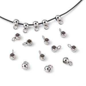 May include: Silver-toned metal bead caps with a loop on the top. The bead caps are arranged in a scattered pattern on a white surface.