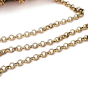 May include: A gold chain with a delicate, round link design. The chain is shown in a close-up view, highlighting the intricate details of the links.