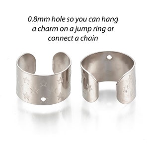 May include: Two silver metal rings with a star pattern and a small hole for attaching a charm or chain. 0.8mm hole so you can hang a charm on a jump ring or connect a chain.