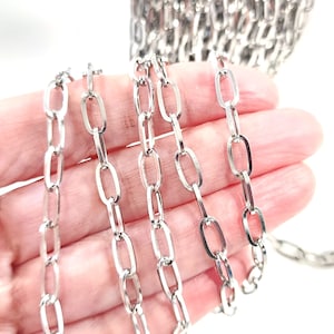 May include: Silver chain with multiple strands of oval links. The chain is made of metal and has a shiny finish.