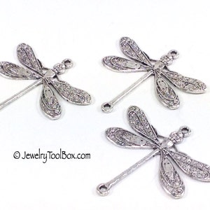 May include: Three silver dragonfly charms with intricate details and a loop at the bottom for attaching to jewelry or crafts.