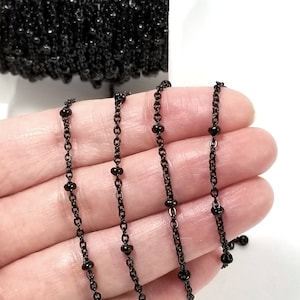 May include: Black chain with small round beads. The chain is made of metal and has a matte finish.