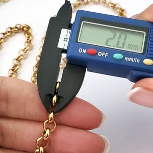 May include: Close-up of a gold chain being measured with a digital caliper. The caliper reads 2.0 mm.