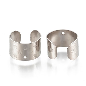 May include: Two silver metal ear cuffs with a star pattern. Each cuff has a small hole on the side.