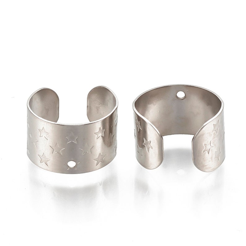 May include: Two silver metal ear cuffs with a star pattern. Each cuff has a small hole on the side.
