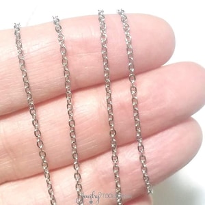 May include: Four strands of silver chain, shown against a hand, for jewelry making.