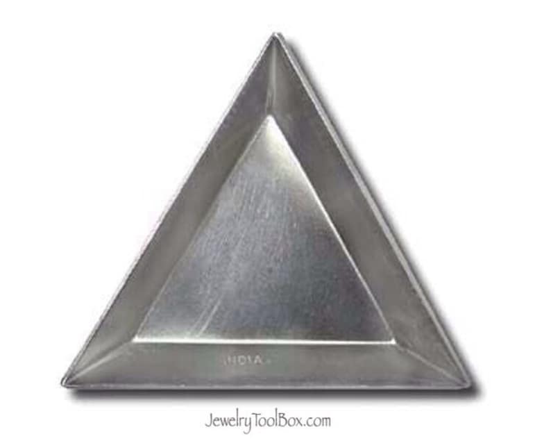 Puede incluir: Una bandeja triangular de metal con un acabado liso y plateado. La bandeja tiene un borde ligeramente elevado y la palabra "INDIA" est&aacute; impresa en la parte inferior.