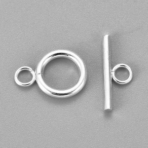 May include: Silver toggle clasp with a round ring and a straight bar. The clasp is used for jewelry making.