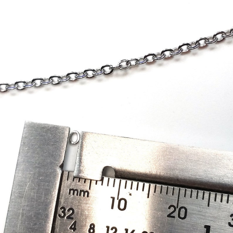 Może przedstawiać: Zbliżenie na srebrny ogniwo łańcucha mierzone linijką. Ogniwo łańcucha ma 32 mm szerokości.