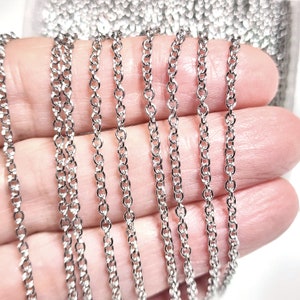 Puede incluir: Varias hebras de cadena plateada, mostradas en una mano, para la elaboraci&oacute;n de joyas.