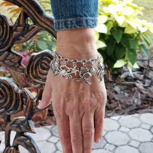 May include: A silver charm bracelet with a variety of sea-themed charms, including a mermaid, crab, starfish, turtle, and seashell.