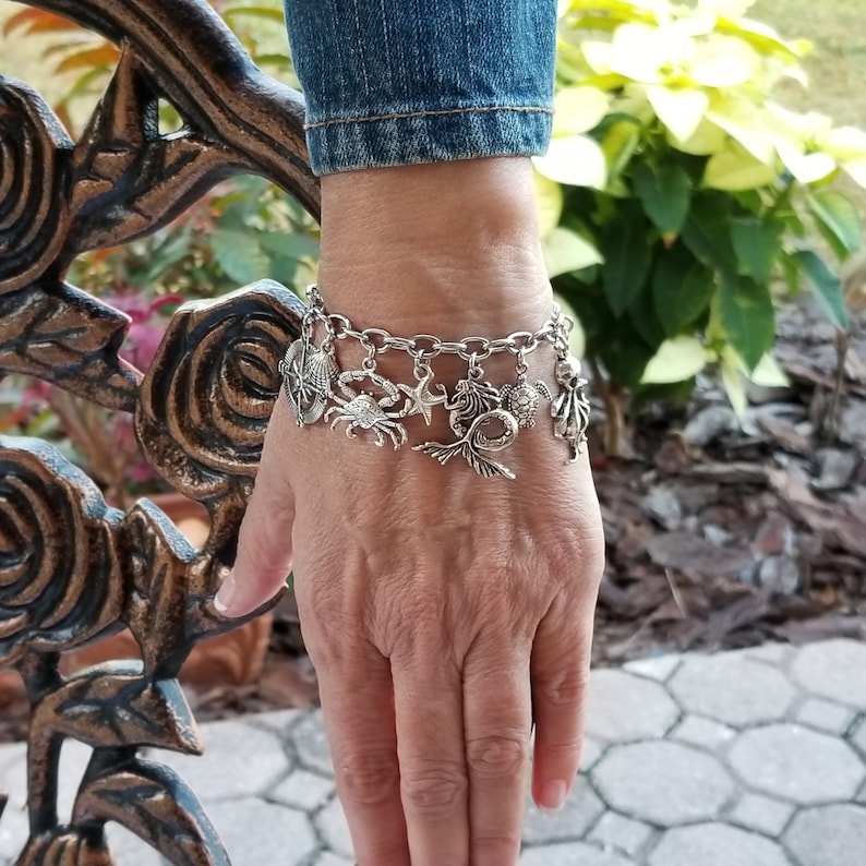 May include: A silver charm bracelet with a variety of sea-themed charms, including a mermaid, crab, starfish, turtle, and seashell.