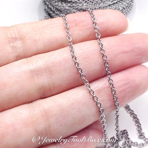 Puede incluir: Un collar de cadena de plata, mostrado en una mano, es una cadena fina y delicada con peque&ntilde;os eslabones redondos.