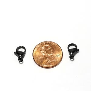 Puede incluir: Dos cierres de langosta de metal negro, cada uno del tama&ntilde;o de una moneda de un centavo de euro.