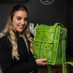 Peut inclure: Un sac à dos en cuir vert citron vif doté d'un grand rabat supérieur avec deux fermetures à pression métalliques, deux poches avant plus petites avec des boutons-pression assortis et une longue bandoulière réglable avec des détails en laiton vieilli.