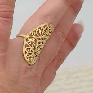 May include: A gold filigree ring with a delicate, intricate design. The ring is open and adjustable to fit most finger sizes.