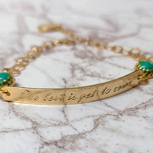 Può includere: Braccialetto in oro con una pietra turchese su ogni estremità e un messaggio inciso che recita "The best is yet to come".