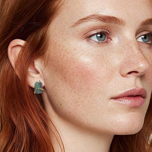 May include: A pair of gold earrings with green gemstone accents. The earrings are small and delicate, and they would make a great gift for someone special.