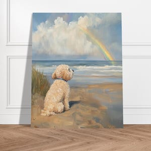 Puede incluir: Pintura de un perro pequeño, esponjoso, de color crema sentado en una playa, mirando un arcoíris sobre el océano. La obra de arte presenta un cielo azul con nubes y una playa arenosa con olas. El perro lleva un collar azul.