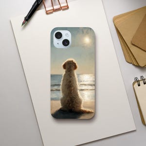 May include: A rectangular smartphone case featuring a printed illustration of a fluffy golden-coloured dog sitting on a sandy beach, facing a calm ocean under a bright sun. The design displays soft, painterly textures and warm light tones.