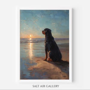 Puede incluir: Pintura enmarcada de un perro negro sentado en una playa, mirando la puesta de sol sobre el océano. La obra de arte utiliza azules, naranjas y marrones. El texto "SALT AIR GALLERY" está en la parte inferior del marco.