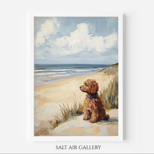 Peut inclure: Peinture à l'huile d'un chien assis sur une plage de sable, regardant l'océan. L'œuvre représente un chien brun et duveteux avec un collier bleu, sur fond de ciel bleu avec des nuages blancs et une mer calme. La peinture est encadrée dans un cadre blanc.