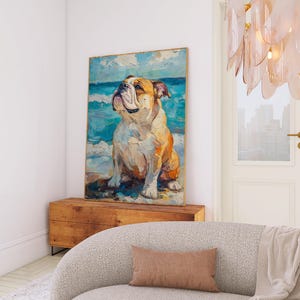 May include: A framed canvas art print featuring a painting of a bulldog on a beach. The artwork depicts the dog with a light brown and white coat, set against a backdrop of blue ocean and sky. The painting is displayed above a wooden chest.