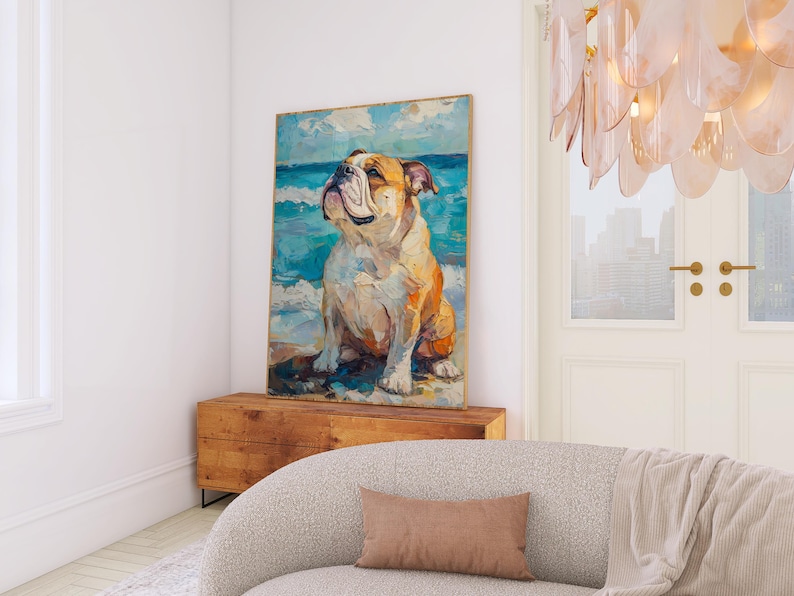 May include: A framed canvas art print featuring a painting of a bulldog on a beach. The artwork depicts the dog with a light brown and white coat, set against a backdrop of blue ocean and sky. The painting is displayed above a wooden chest.