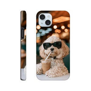 Könnte beinhalten: Eine Smartphone-Hülle mit einem Fotodruck eines hellen, lockigen Hundes, der eine schwarze Sonnenbrille trägt. Der Hund befindet sich hinter einem durchsichtigen Plastikbecher, der mit einem hellbraunen Eiskaffee und einem weißen Strohhalm gefüllt ist.